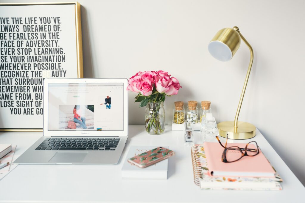 Foto van een bureau met laptop en veel roze accesoires