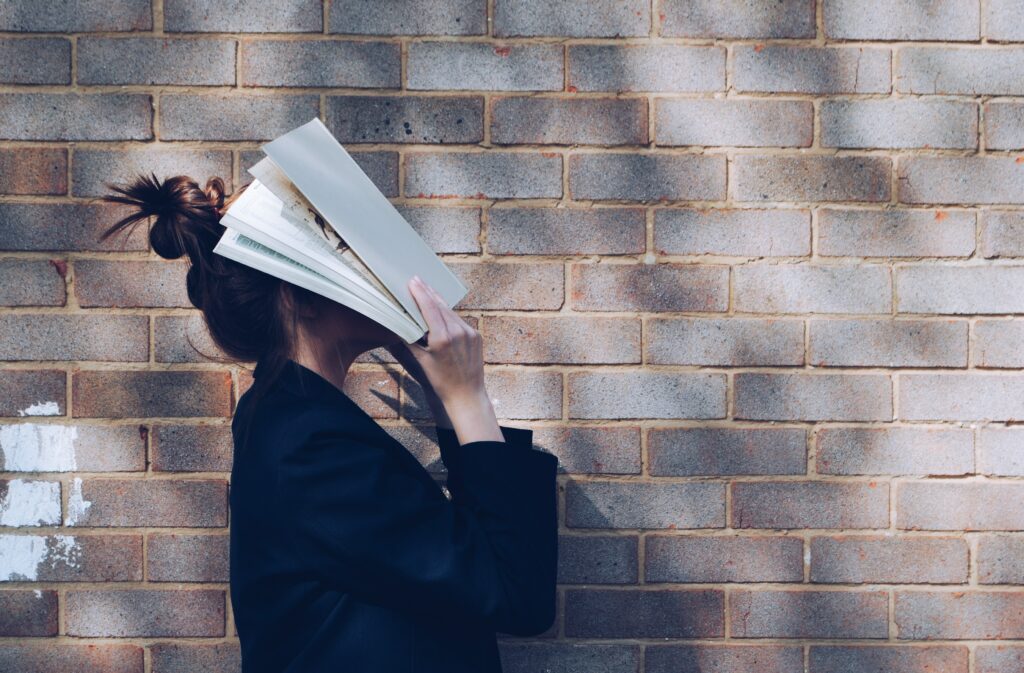 vrouw met boek op haar hoofd als weergave van het lezen van een tekst die niet op B1-niveau is geschreven