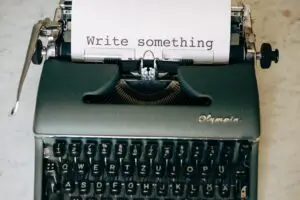 typemachine met papier waarop 'write something' staat.