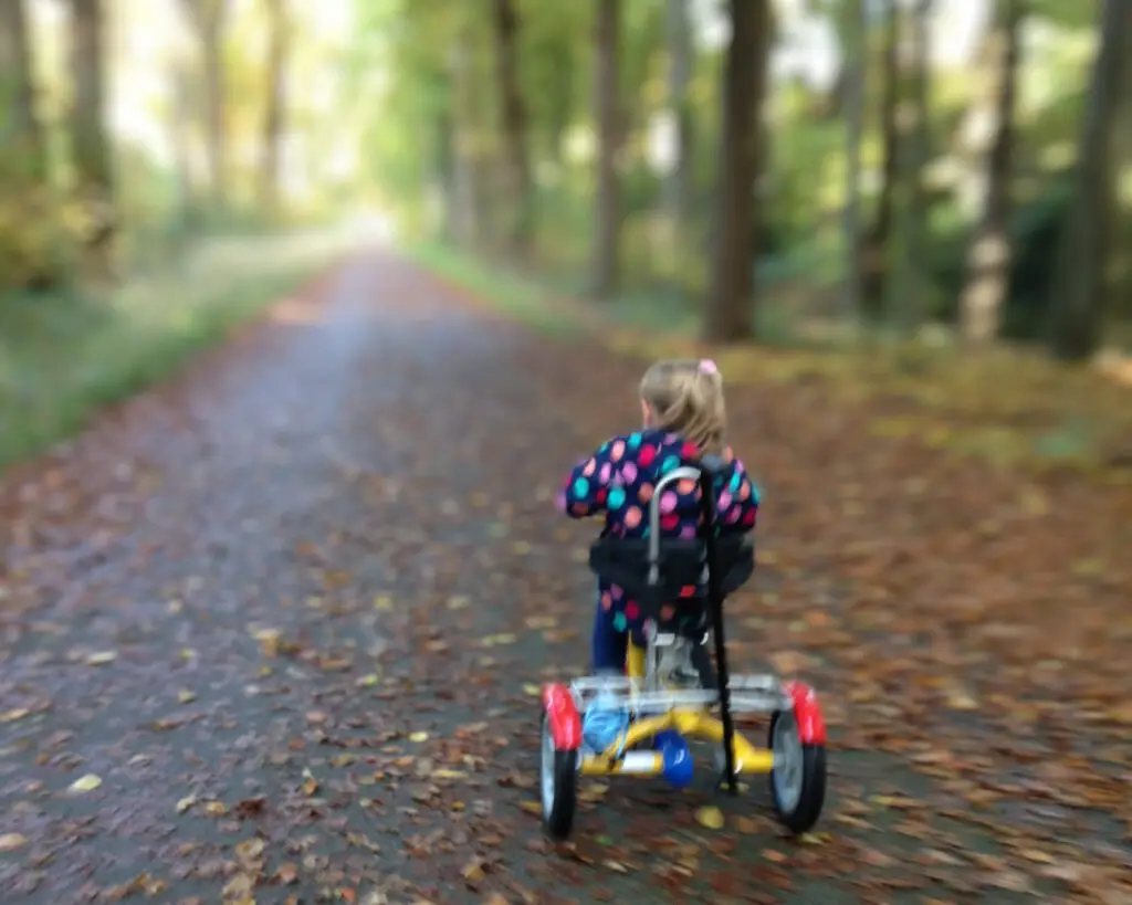 Kind op aangepaste driewielfietsn in het bos